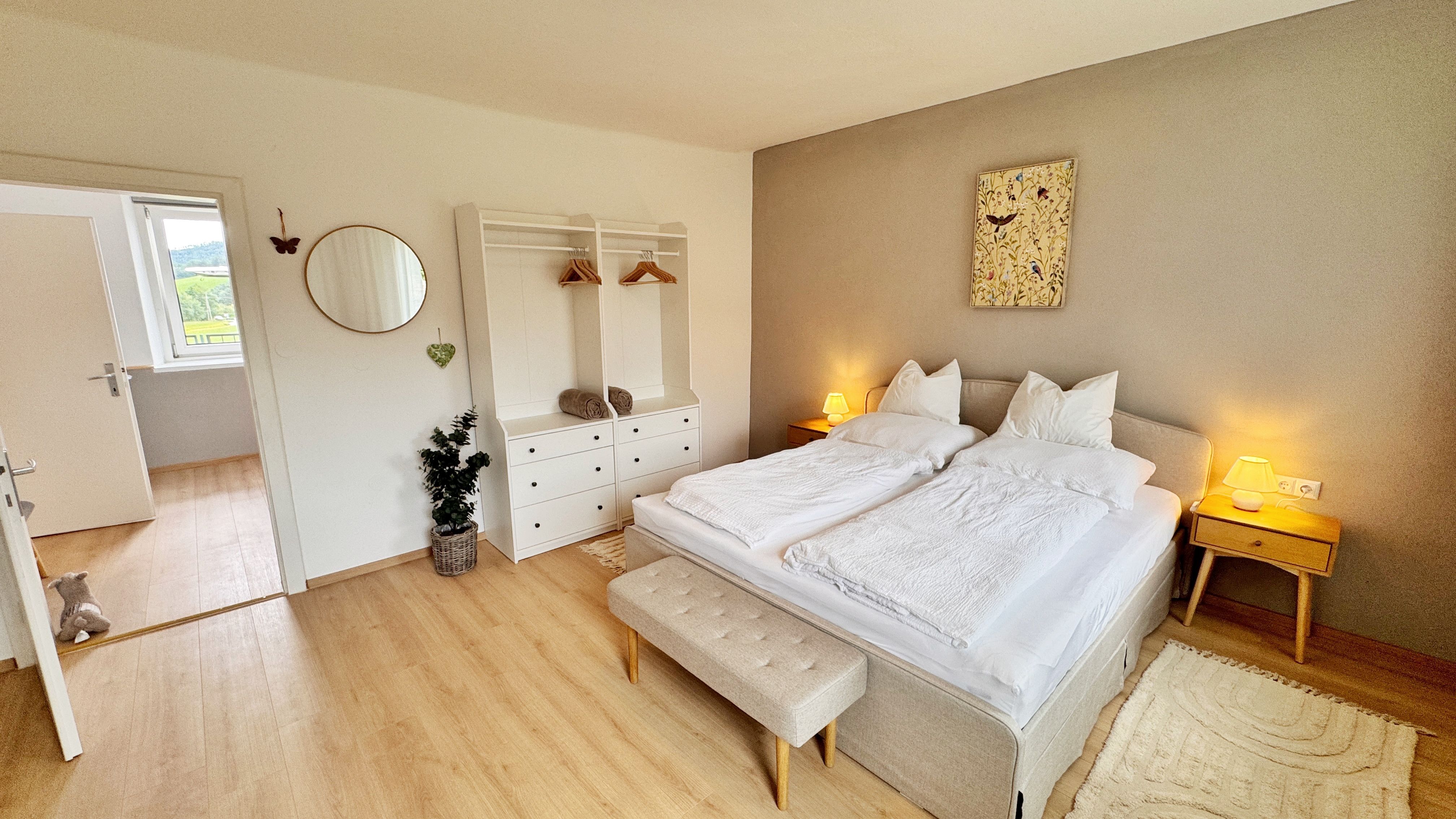 Ein gemütliches Schlafzimmer mit Doppelbett, Nachttischen, Kleiderschrank und Dekoration.