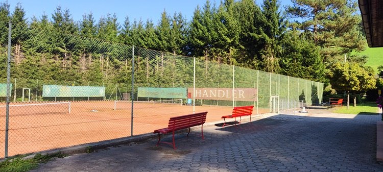 Tennisplatz mit rotem Sand und Bänken in Bad Schönau.