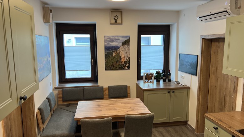 Modern kitchen with wooden furniture, dining table and green cupboards.
