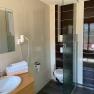 Modern bathroom with washbasin, mirror, towels, toilet and shower.