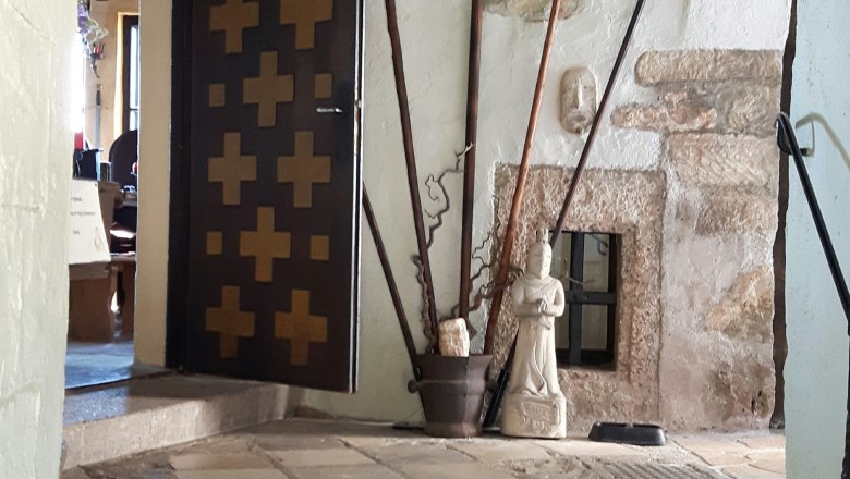 Innenansicht einer Burg mit Waffen, einem Wildschweinkopf und einer Statue.