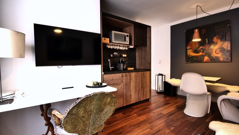 Moderne Küche mit Holzelementen, Flachbildfernseher und Essbereich.