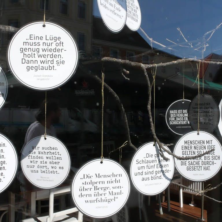 Runde Schilder mit Zitaten hängen in einem Schaufenster.