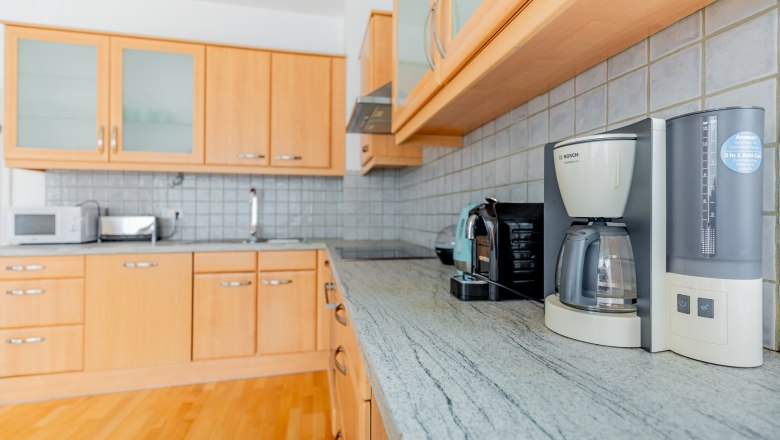 Moderne Küche mit Holzschränken, Kaffeemaschine und Toaster auf der Arbeitsplatte.