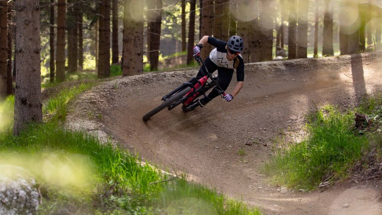 Mountainbiker fährt durch einen Wald auf einem kurvigen Trail.