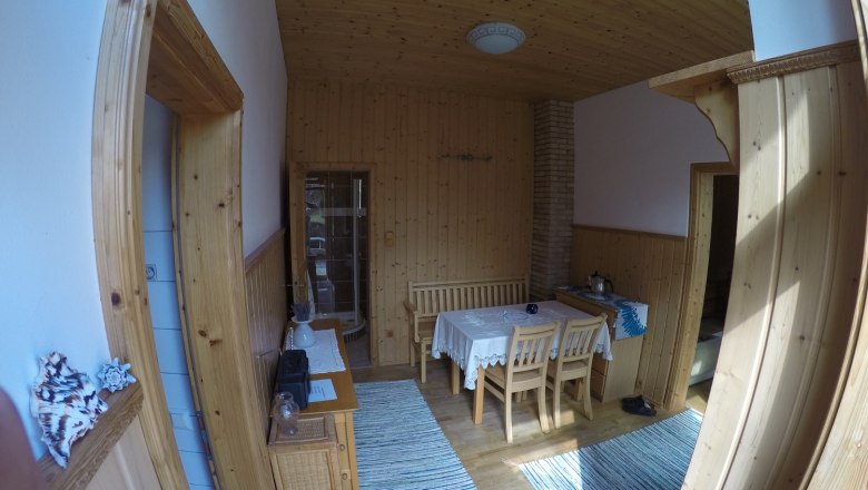 Esszimmer mit Holzwänden, Tisch und Stühlen, Teppichen und Dekorationen.