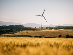 Das Windrad Lichtenegg auf einem Feld, im Hintergrund Berge