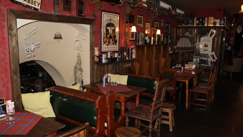 Cozy bar with wooden furniture, red walls and Irish decorations.