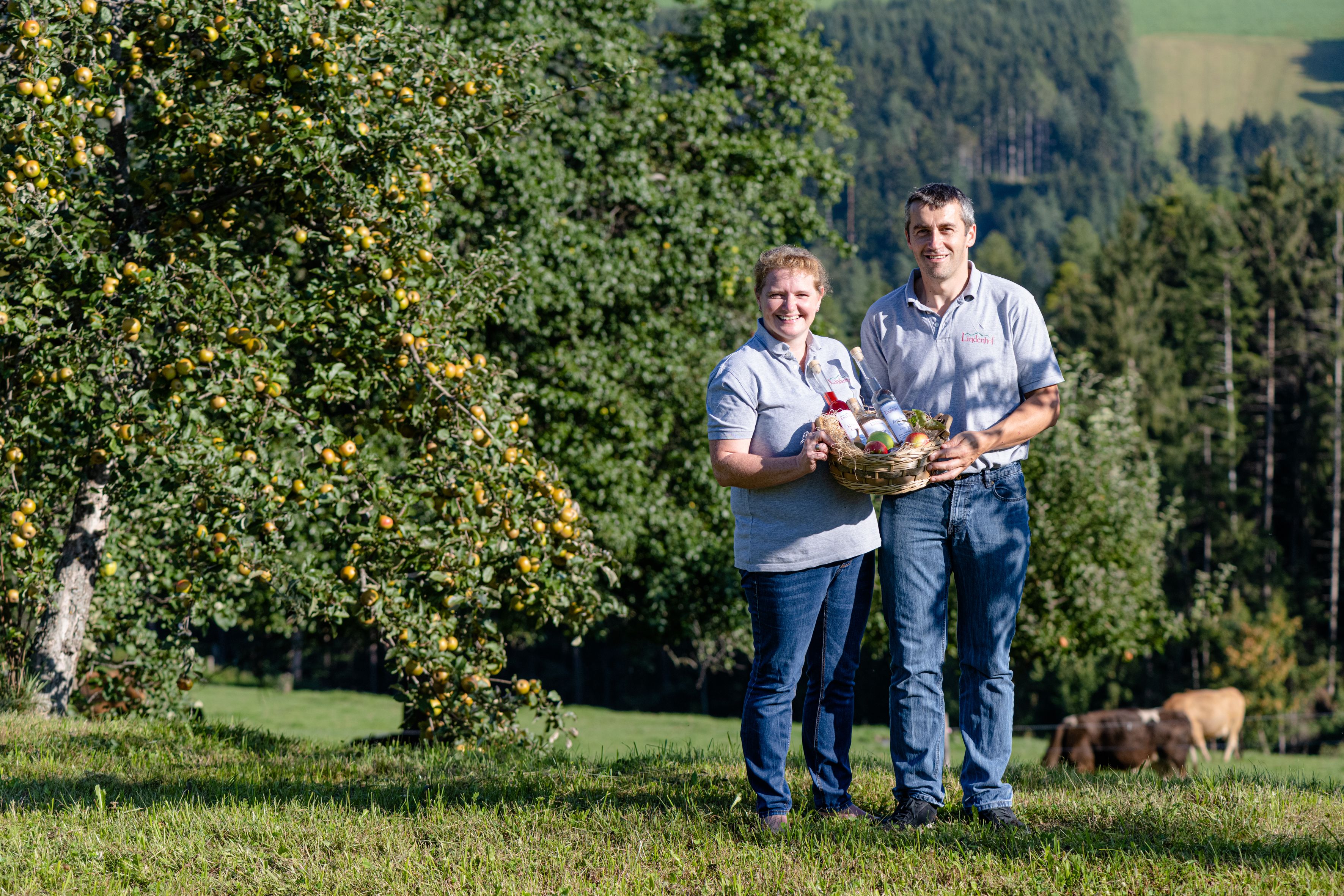 Ein Mann und eine Frau halten einen Korb auf einer grünen Wiese.