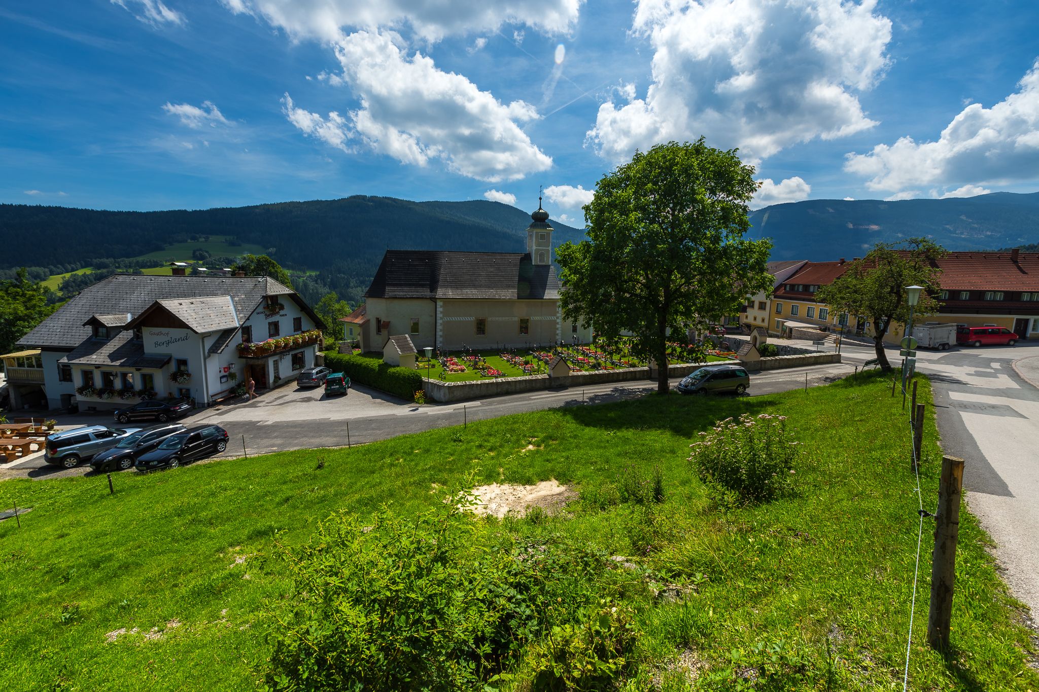 Ländliche Szene mit Kirche, Gasthaus und grüner Wiese in Aspangberg-St. Peter.