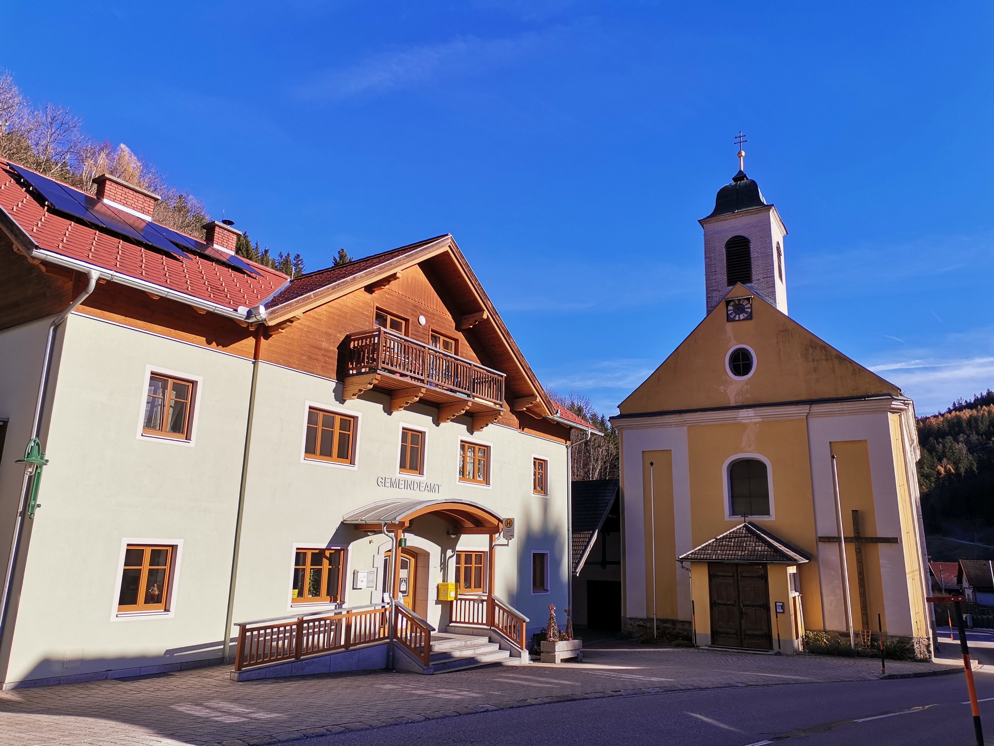Gemeindeamt und Kirche in Trattenbach bei sonnigem Wetter.