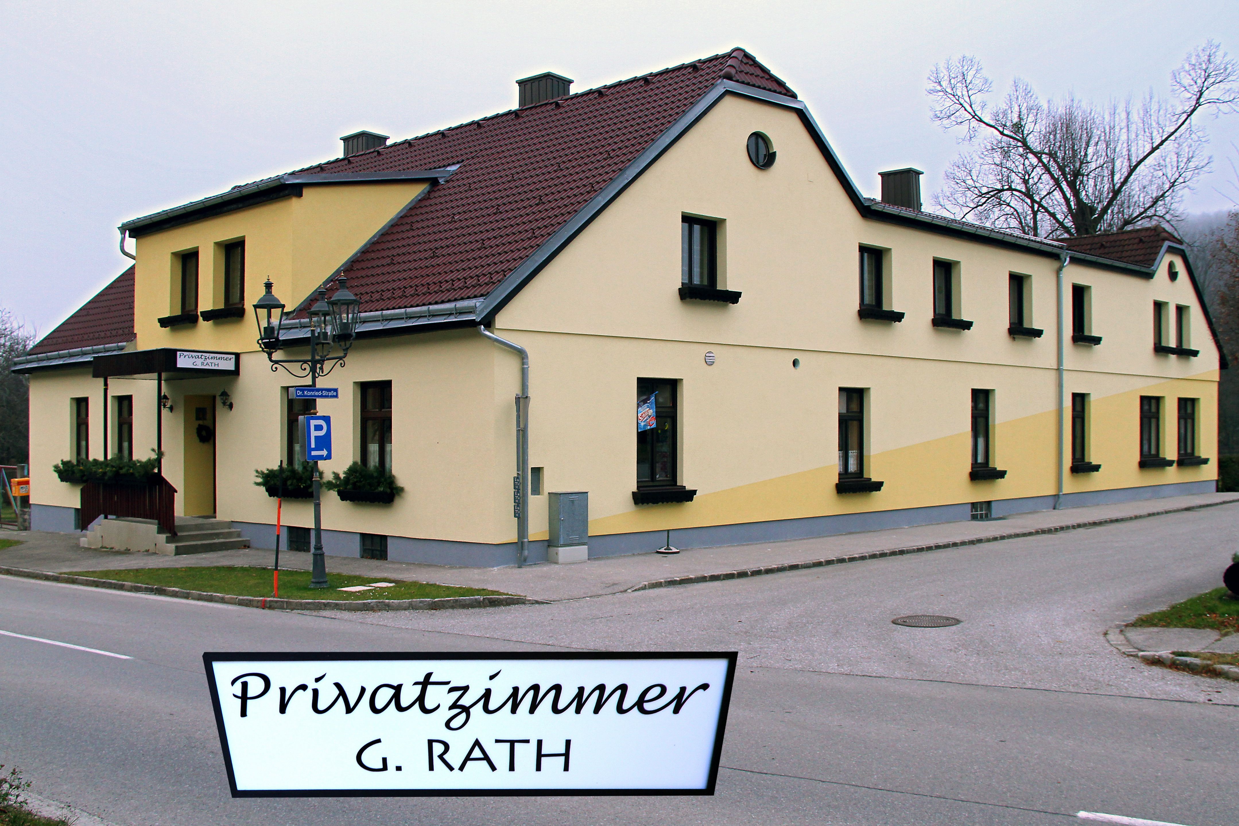 Gelbes Gebäude mit rotem Dach und Schild 'Privatzimmer G. Rath'.