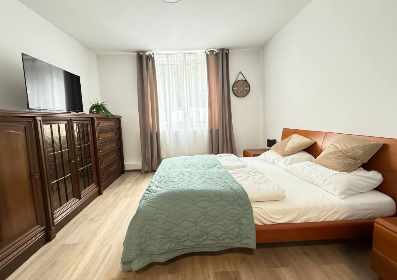 Ein gemütliches Schlafzimmer mit einem großen Bett, Holzmöbeln und einem Fernseher an der Wand.