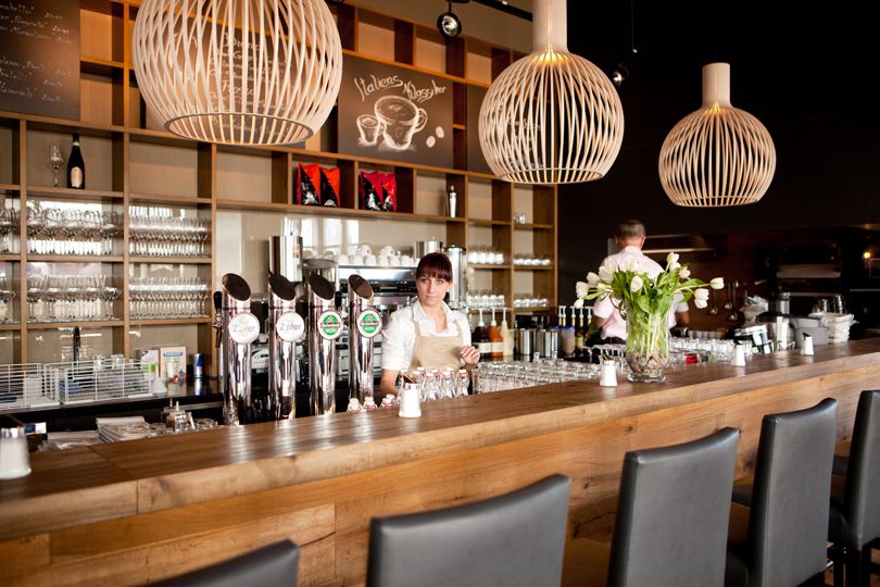 Moderne Bar mit Holztheke, Zapfhähnen und dekorativen Lampen.
