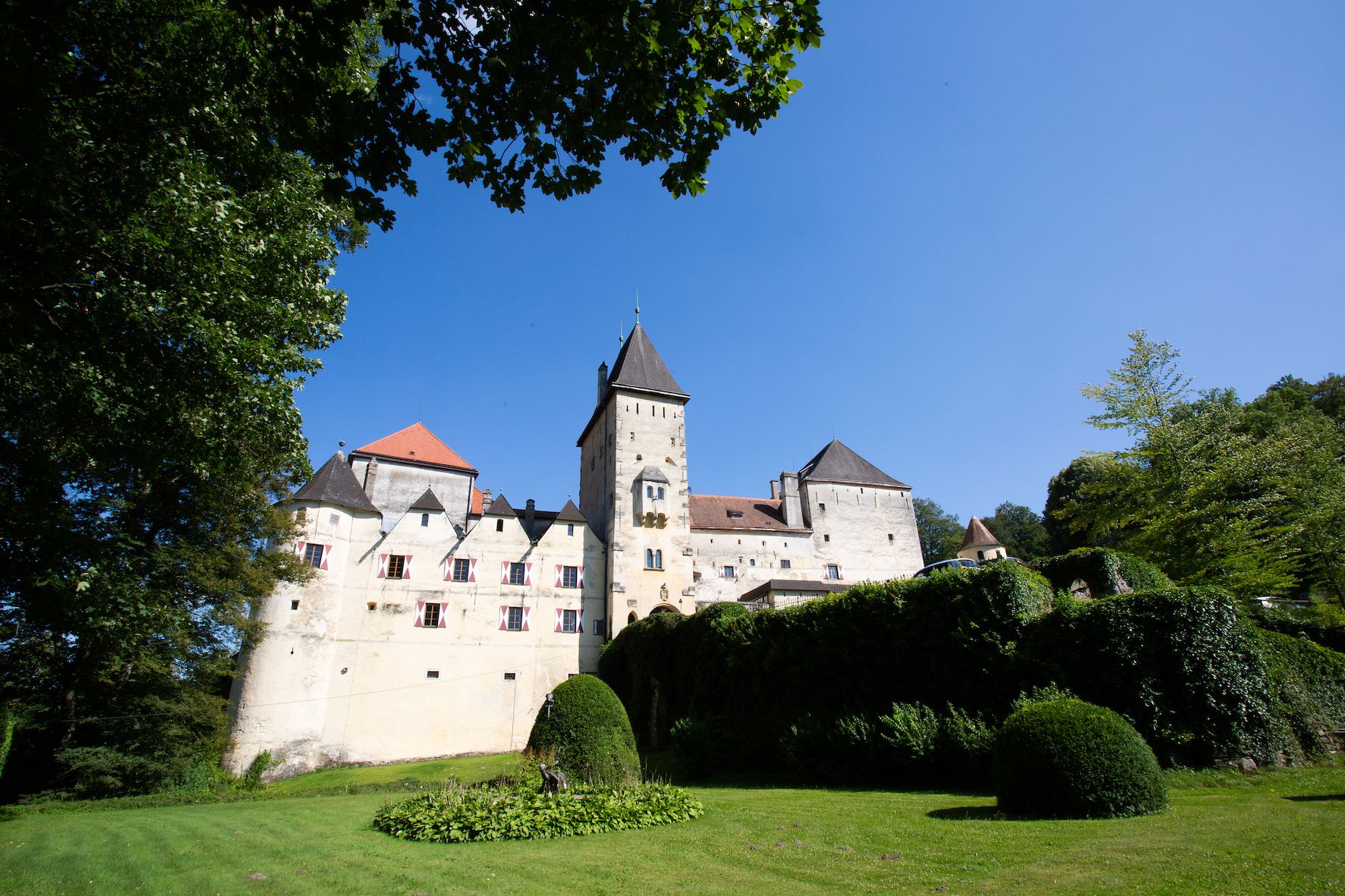 Burg Feistritz mit blauem Himmel und grüner Landschaft.