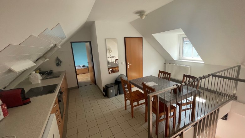 Wohnk&uuml;che mit Esstisch, St&uuml;hlen, K&uuml;chenzeile und Dachschr&auml;ge.