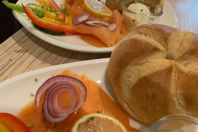 Frühstücksteller mit Lachs, Zwiebeln, Zitrone, Paprika und Brötchen.