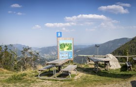 Picknicktische und Wanderschild mit Bergblick bei der Edelweißhütte am Schneeberg.