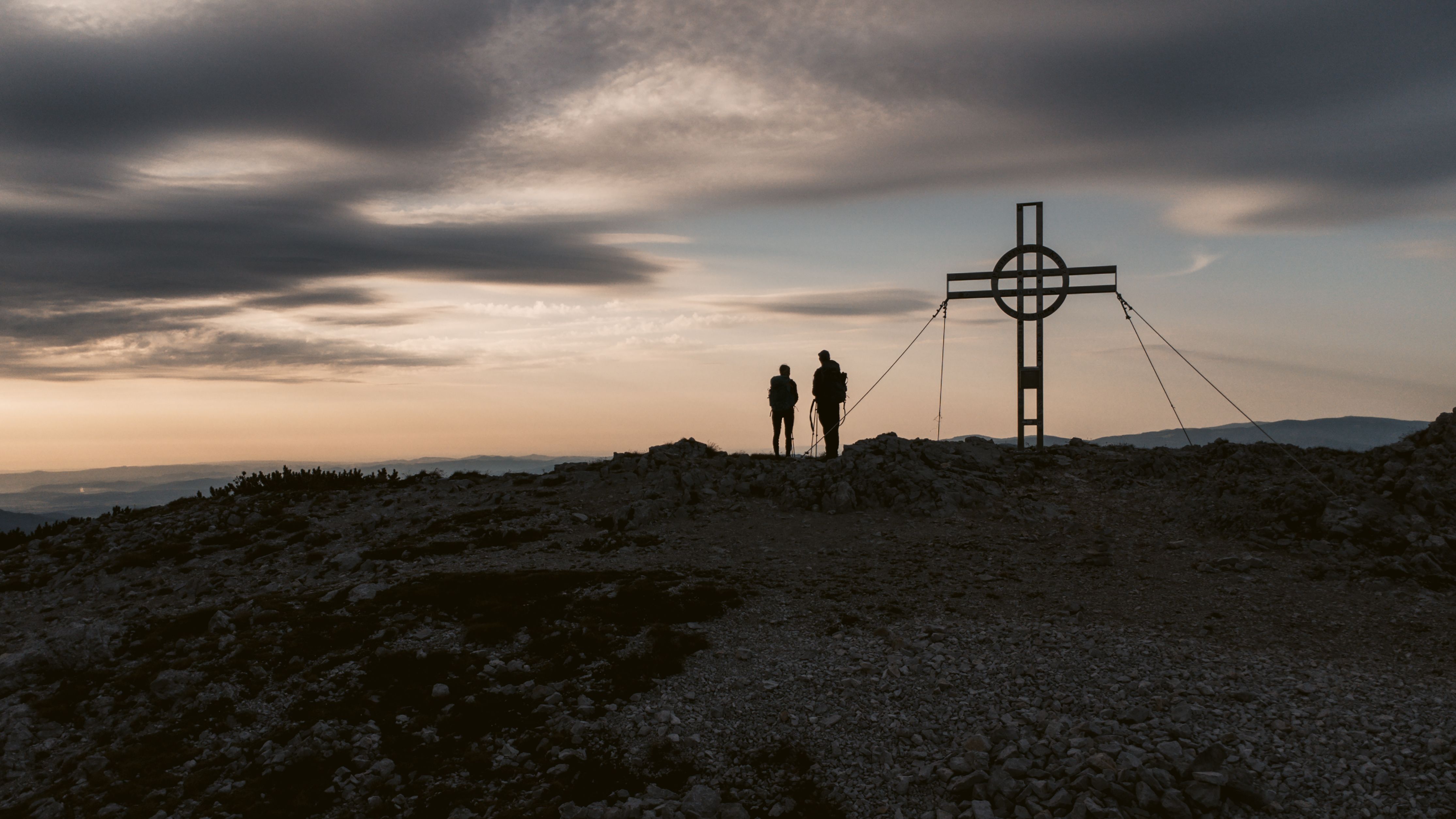 Ein Wanderer genießt den atemberaubenden Sonnenuntergang über den majestätischen Bergen, während die sanften Hügel in warmen Goldtönen erstrahlen. Die frische Bergluft und die unberührte Natur schaffen eine perfekte Kulisse für unvergessliche Erlebnisse in den Wiener Alpen.