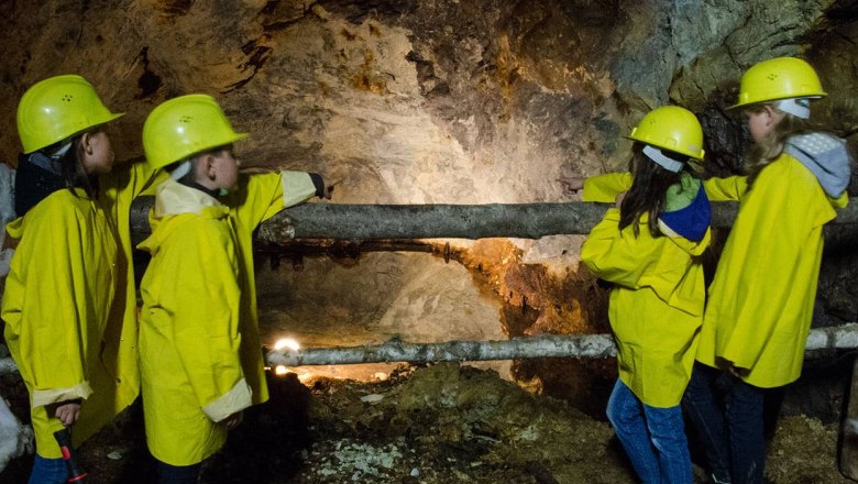 Kinder in gelben Helmen und Mänteln in einem Schaubergwerk.