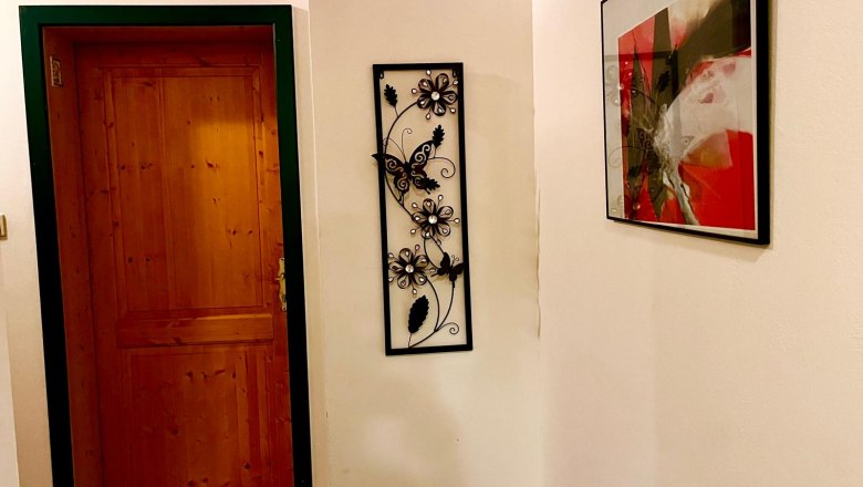 Flur mit Holztür, Wanddekoration und abstraktem Bild.