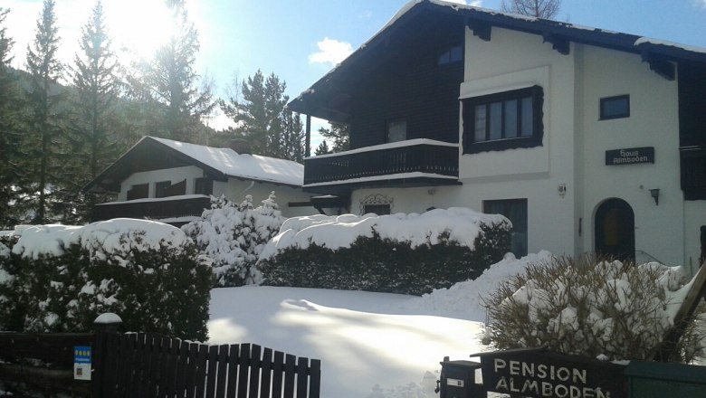 Snow-covered house with 'Pension Almboden' sign in the foreground.