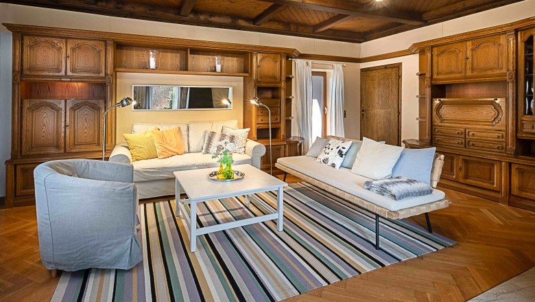 Cozy living room with wooden furniture, sofas, carpet and coffee table.