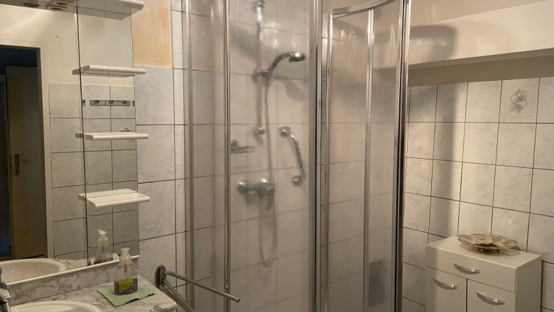 Badezimmer mit Dusche, Waschbecken und Spiegel.