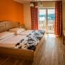 Comfortable hotel room with double bed, wooden furniture and balcony with a view.