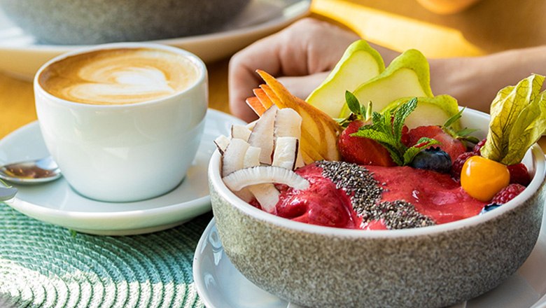 Frühstück mit Kaffee und Smoothie-Bowl mit Obst und Chiasamen.
