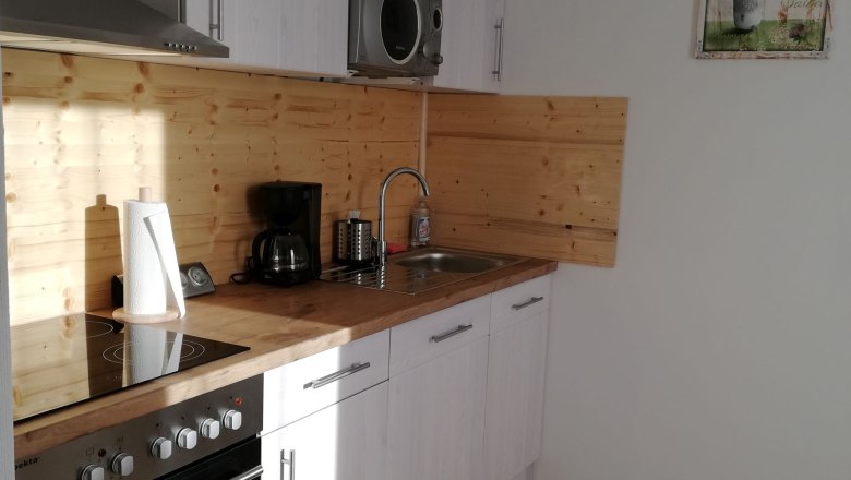 Moderne Küche mit Holzverkleidung, weißen Schränken und Geräten.