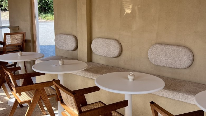 Innenbereich eines Cafés mit Holzmöbeln und runden Tischen.