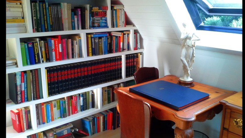 Ein gemütlicher Arbeitsbereich mit Bücherregal, Schreibtisch und Statue.