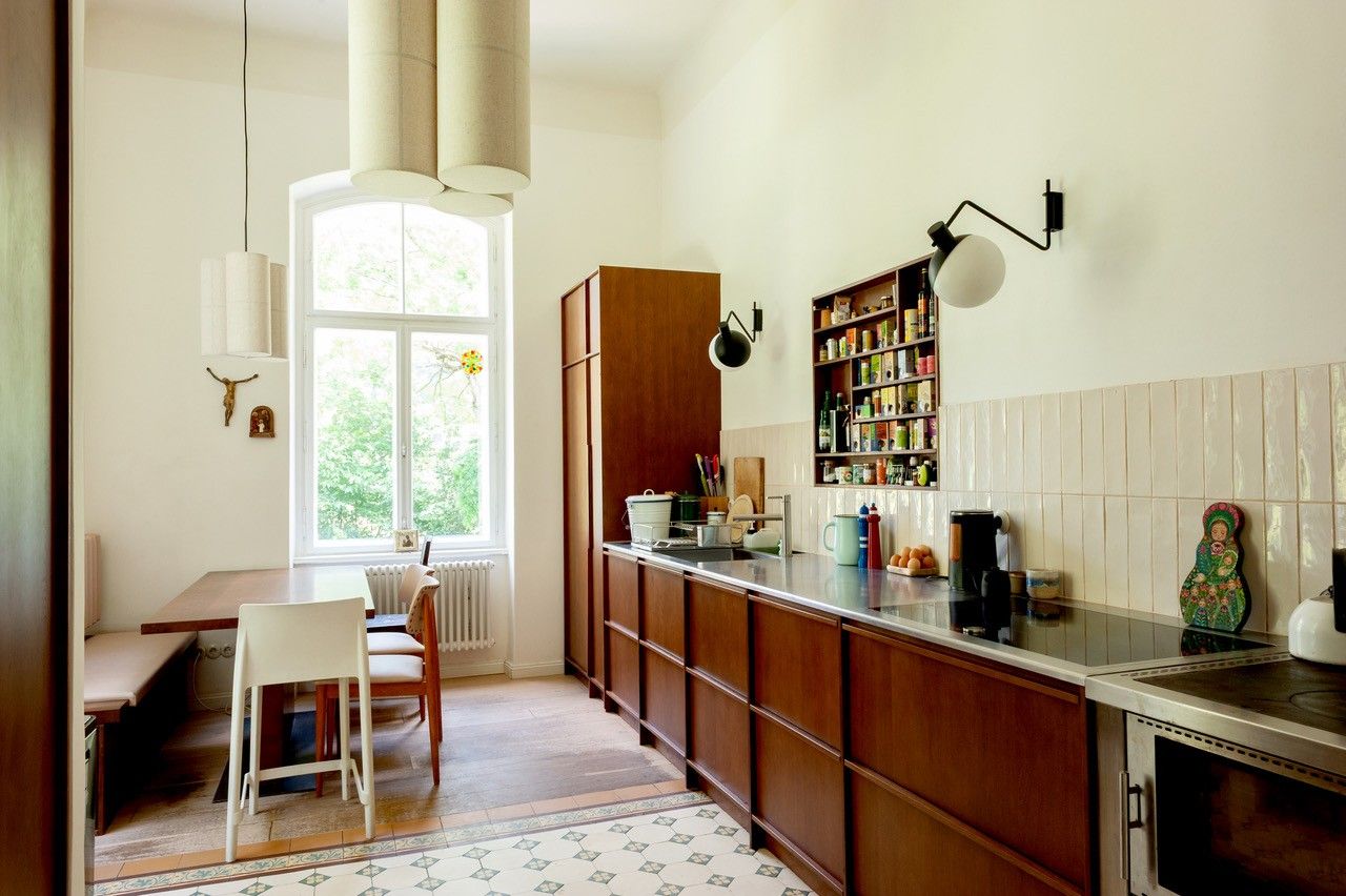 Eine moderne Küche mit Holzmöbeln, einem großen Fenster, einem Esstisch und einer gut ausgestatteten Arbeitsfläche.