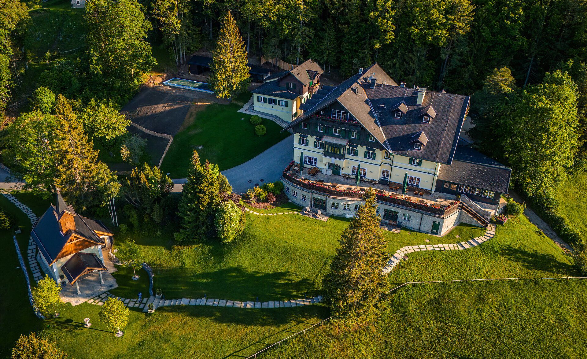 Umgeben von üppigem Grün und majestätischen Bäumen, strahlt der Knappenhof eine einladende Ruhe aus. Die harmonische Architektur des Gebäudes fügt sich perfekt in die malerische Landschaft der Wiener Alpen ein und lädt dazu ein, die Schönheit der Natur zu genießen.