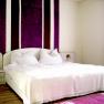 Bedroom with white bed and purple stripes on the wall.