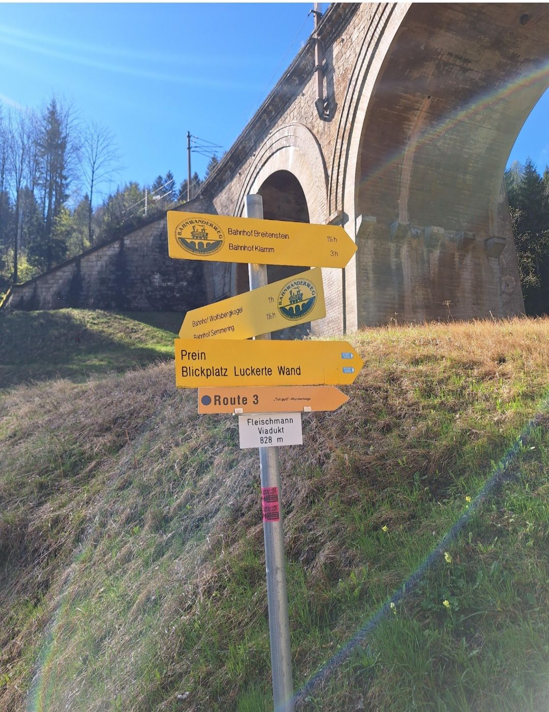 Steher mit 4 gelben Wandertafeln in Breitenstein, dahinter ist ein Viadukt zu sehen