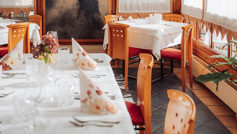 Elegantes Restaurant mit gedeckten Tischen, Holzstühlen und dekorativen Servietten.