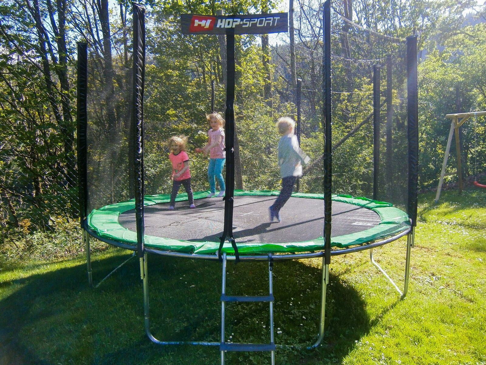 Drei Kinder springen auf einem Trampolin im Freien.