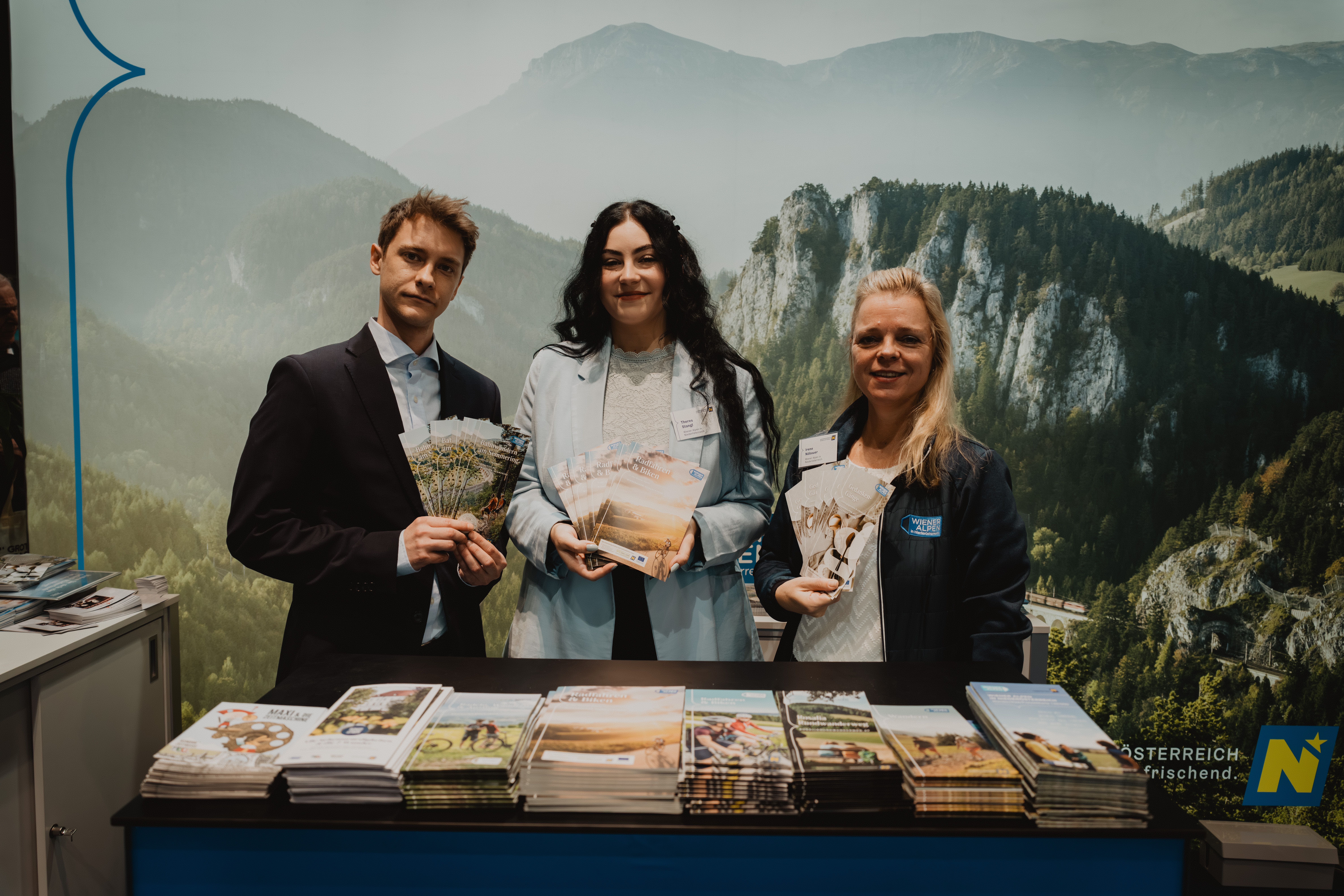 Ein Mann und zwei Damen vor dem Wiener Alpen Stand