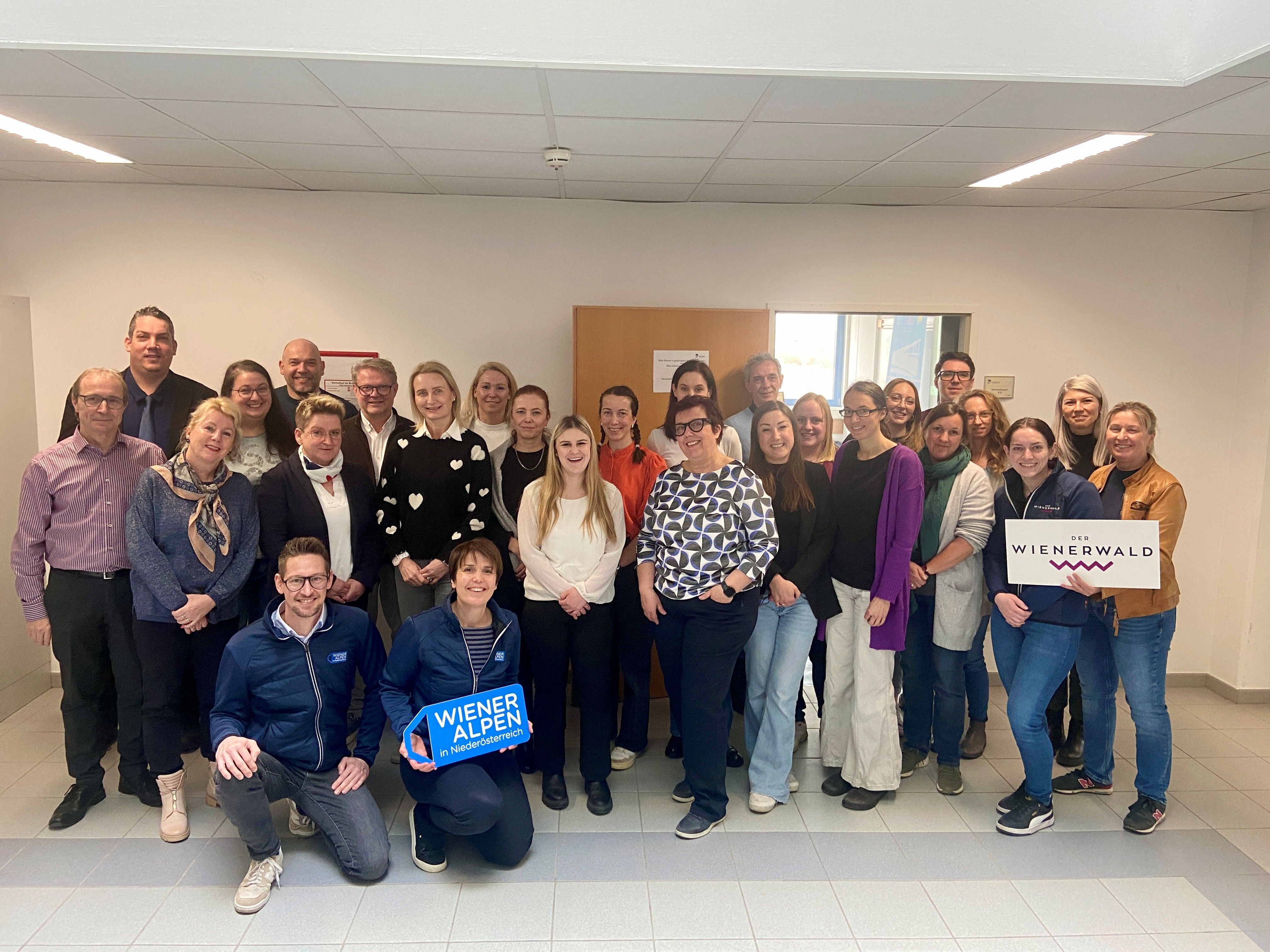 Rund 25 Teilnehmer eines Workshops stehen für ein Gruppenbild zusammen und halten ein Wiener Alpen Schild und ein Wienerwald Schild in ihren Händen.