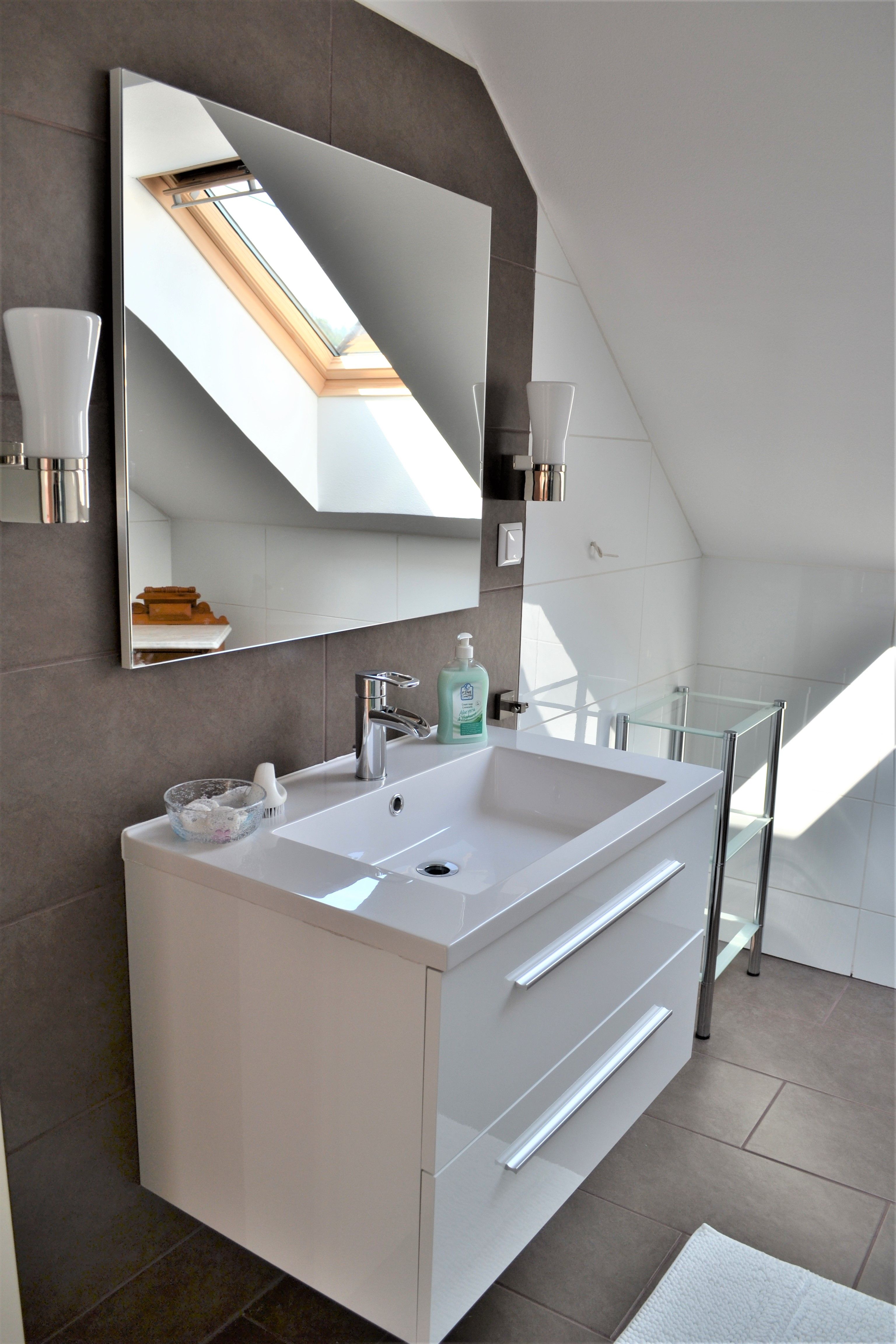 Modernes Badezimmer mit Waschbecken, Spiegel und Dachfenster.