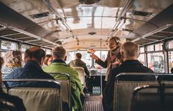 Einige Leute fahren mit dem Oldtimerbus und schauen sich die Stadt an. 