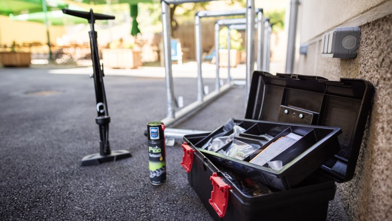 Fahrradwerkzeug, Kettenöl und Pumpe neben Fahrradständern im Freien.