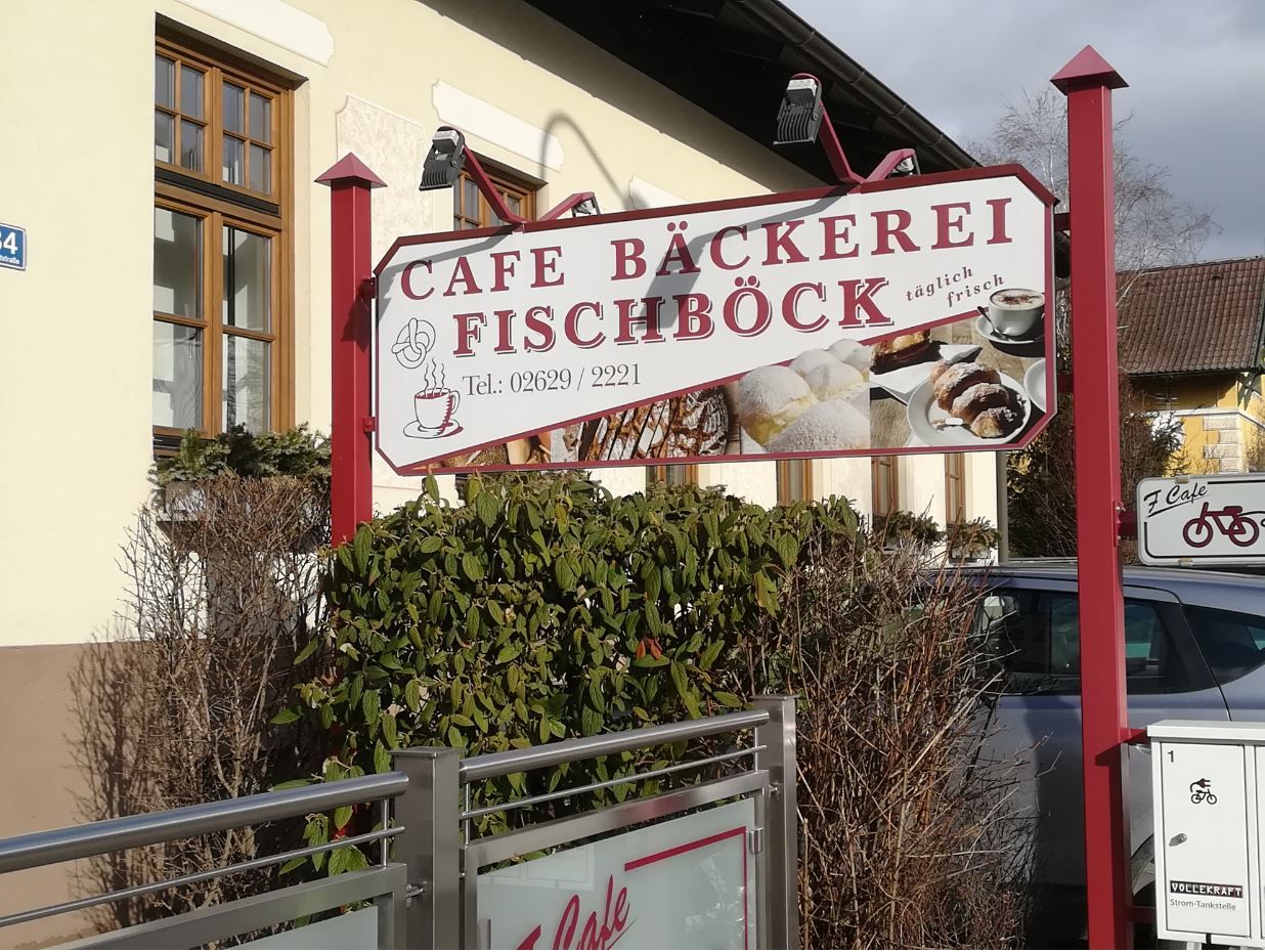 Schild der Café-Bäckerei Fischböck mit Gebäckabbildungen und Telefonnummer.
