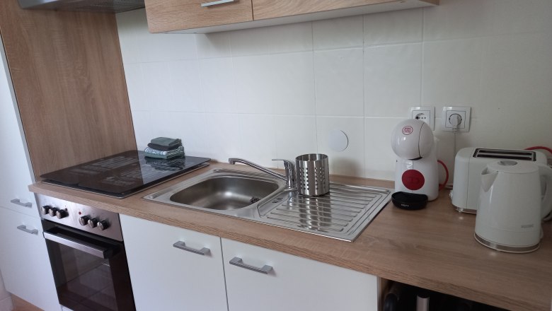 Moderne K&uuml;chenzeile mit Herd, Sp&uuml;le, Kaffeemaschine, Toaster und Wasserkocher.