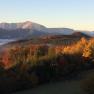 Herbstlandschaft mit bunten B&auml;umen und Bergen im Hintergrund bei Sonnenaufgang.