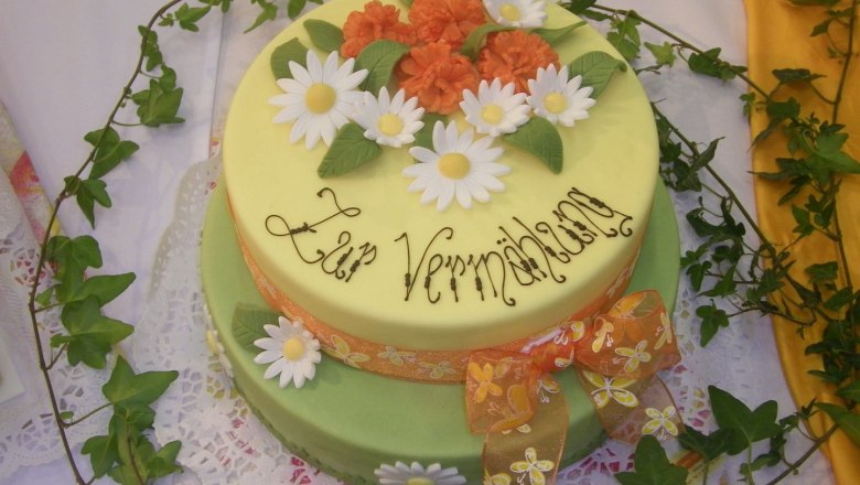 Zweistöckige Torte mit Blumen und Schriftzug 'Zur Vermählung'.