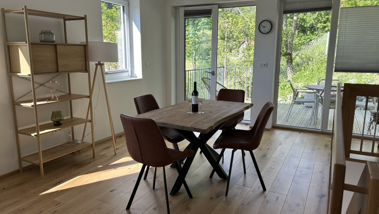Esszimmer mit Holztisch, braunen St&uuml;hlen und Blick auf Terrasse und Garten.