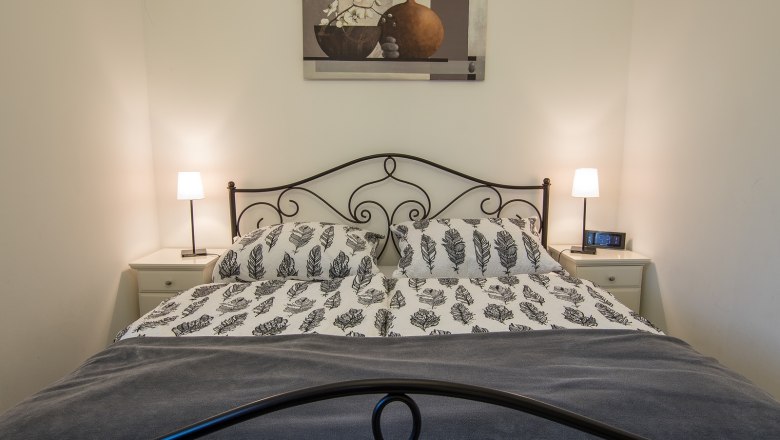 Schlafzimmer mit Doppelbett, zwei Nachttischen und Lampen.